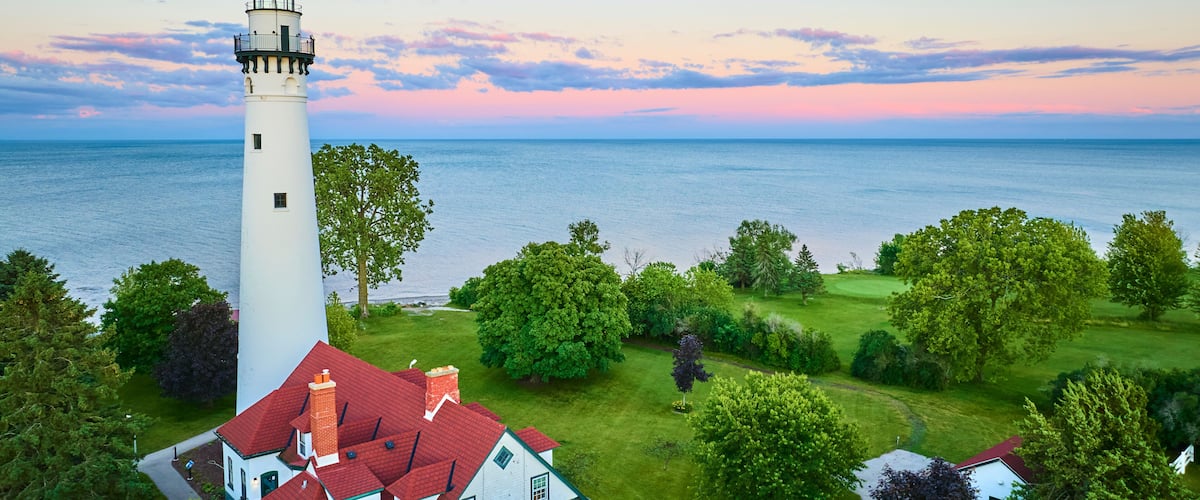 A lighthouse, a grassy field, and a body of water.