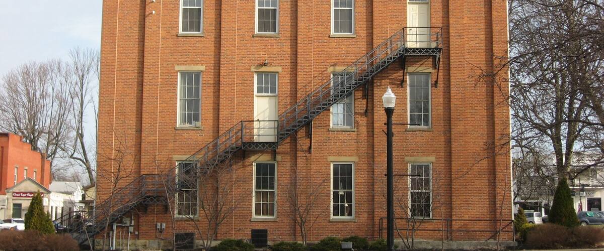 A red brick building with a white dome and a black staircase.