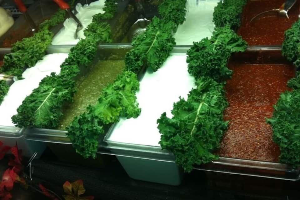 A salad bar with various greens and dressings.