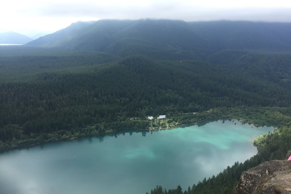 A lake surrounded by dense forest and mountains.