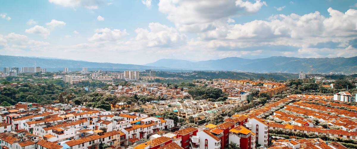 A cityscape with red-roofed buildings and a mountainous backdrop.