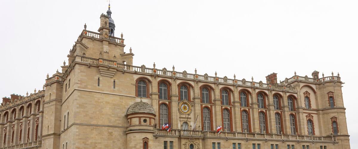 A large historic building with multiple arches and flags.