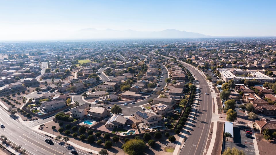 A suburban neighborhood with a curved road, residential houses, and a distant mountain range.