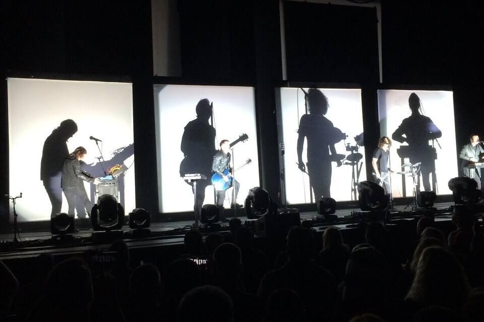 Een band treedt op op een podium voor een groot publiek.