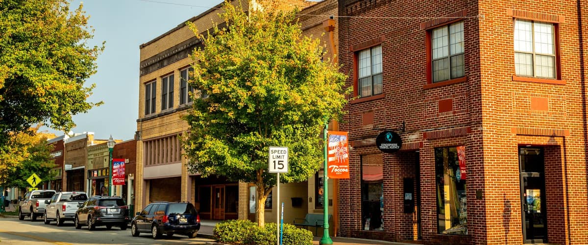 A street lined with brick buildings, a speed limit sign, and parked cars.