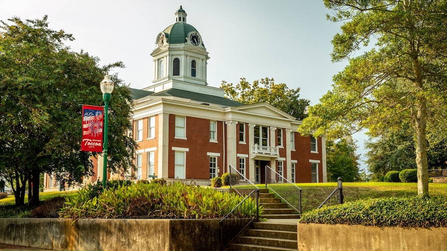 A historic building with a clock tower, surrounded by trees and a flag.