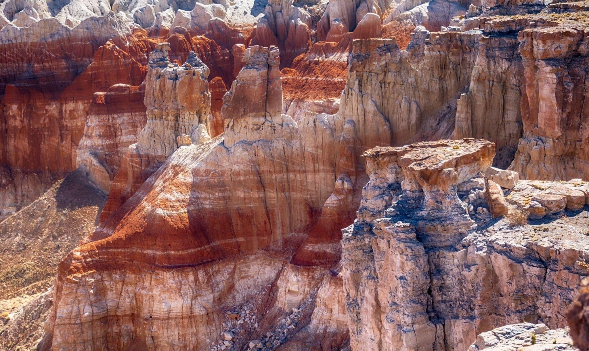 A rugged canyon with prominent red rock formations and layered sedimentary cliffs.