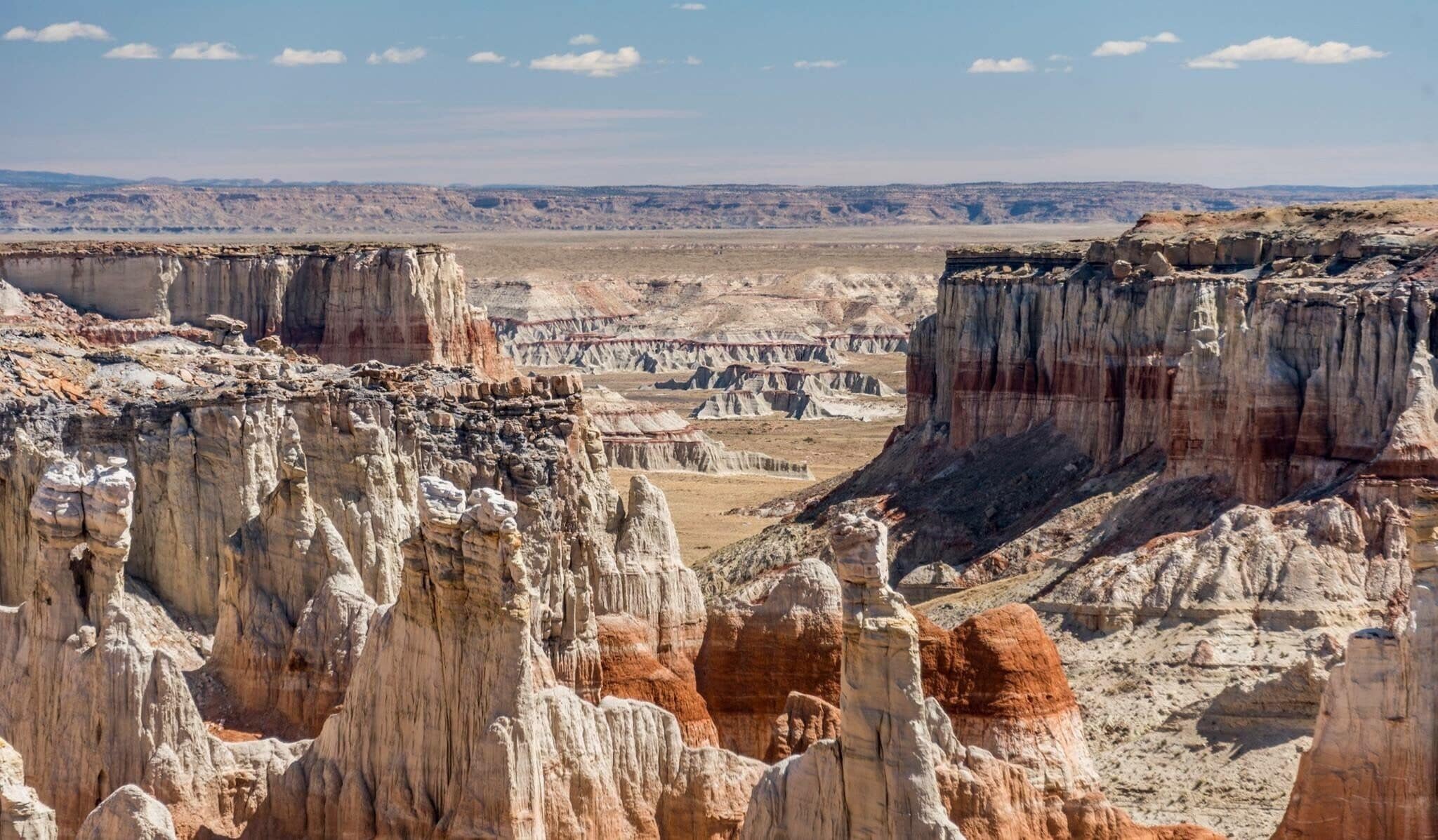 A rugged canyon landscape with prominent rock formations and layered sedimentary cliffs.