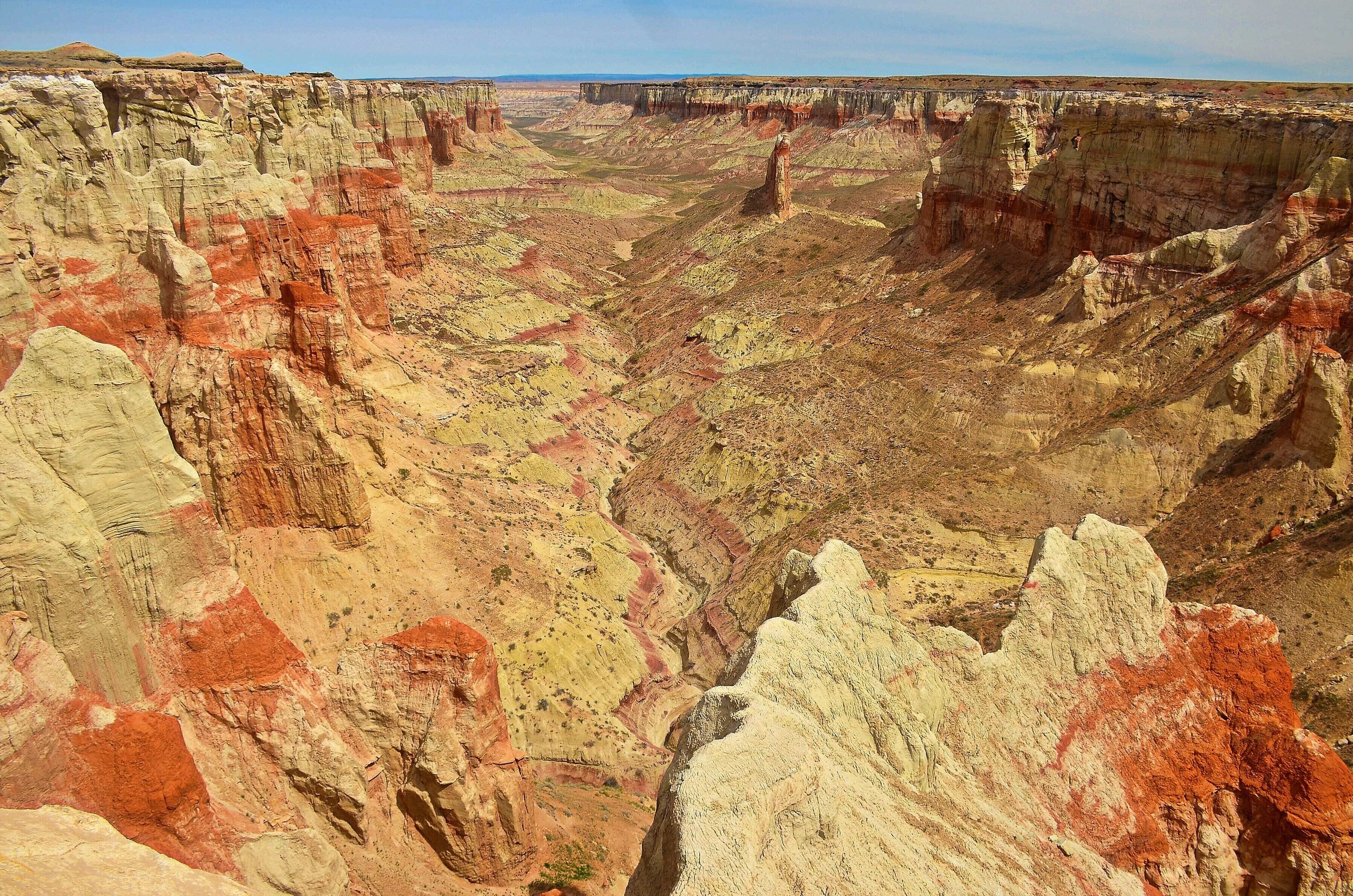 #Nature
Luckily I had the directions to Coal Mine this time, because there is no sign, it’s on private property and you can’t see it from the road.  Between mileposts 363 and 364 you turn off onto someone’s property and aim between a two-storey house and a windmill.  It’s okay, they’re about half a kilometre apart.
I pulled up beside a photogenic ruin and grabbed my gear.  As I stood up, the attraction of Coal Mine became clear.  It was everything I’d hoped for and more.  The reality of it was simply that it was the finest canyon I’d ever seen.
Sure, it’s not as deep as the Grand Canyon, doesn’t have as many hoodoos as Bryce, doesn’t quite have the sheerness of Zion and has no more colour than Cottonwood Canyon Road; but, it has everything; all of those features crammed into one of the earth’s most magnificent compact canyons.  Why it’s not a major attraction I don’t quite understand; perhaps it’s where it is that causes people to miss it.  This would be backed up by the fact that other nearby canyons are rarely visited also.  Perhaps it’s because this is distinctly Indian country, as was the Square Butte earlier.  All along the main routes you see stalls selling jewellery.  I couldn’t help but think if they got a bit entrepreneurial they could make an absolute killing by developing some of the sites.
Still, I was more interested in this washed out hole in the ground.  It’s on the edge of the 120 mile wide Painted Desert. The colours were the like of which I’d never seen before in one geological place.  I moved around to parts where you could get out to; couldn’t stop shaking my head at what was there in front of me.  Weird shapes, the layer of coal that used to be mined almost on top, the patterns in the rocks; I didn’t know where to look first.
After I’d spent over an hour poking in here and there I worked my way further south until I came across the benches that someone has put there.  However, to my despair, I noticed there’s also a rope-supported trail to the bottom just a bit further on.  Physically, I hadn’t enough left in me to go down but, know when you go that it’s an option.  If you want to get to this point first you should drive to the side where the windmill is.
I’ve read another report since on another site that indicates you can drive to two other access points as well, further down the road, but I was unaware of those at the time.  Also, you’ll read that you are on Indian land and, from every bit of information I could glean, it’s Navajo up the top and Hopi down the bottom.  I’d boldly suggest you do just what myself and most people do; just go there.  I tried to contact the Hopi re a trip to Blue Canyon but ran up a dead end, so I gave up after that.
So, if you’re looking for a café and accommodation beside a major attraction, you’ve come to the wrong place.  However, if it’s solitude and a wonderful natural experience that fits the bill, then look no further.
