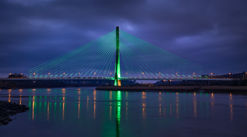 Modern line bridge illuminated with green lights for St. PAtricK in Waterford Ireland. Overnight.