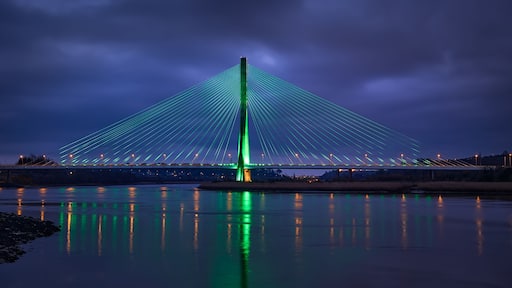 Modern line bridge illuminated with green lights for St. PAtricK in Waterford Ireland. Overnight.