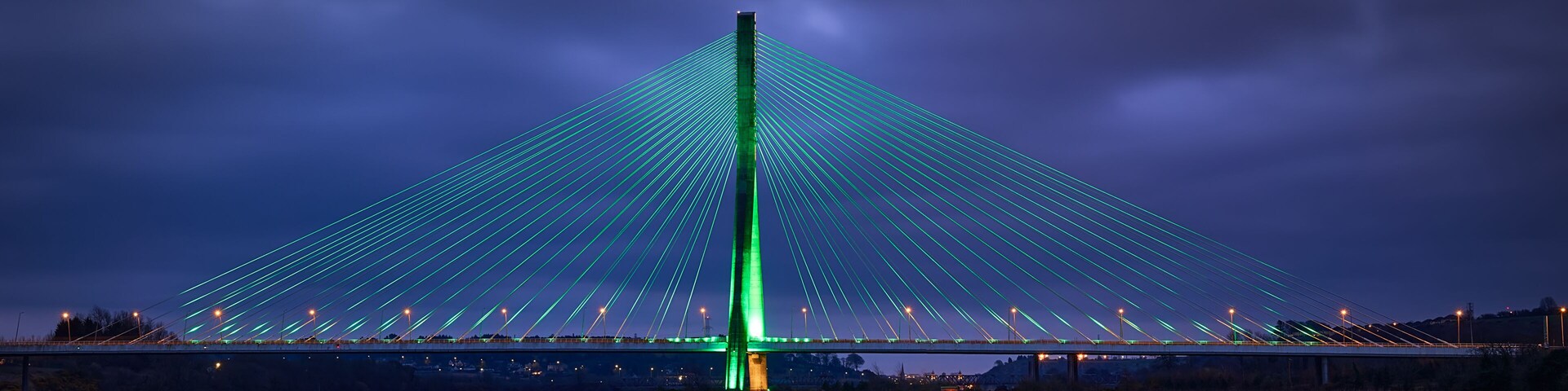 Modern line bridge illuminated with green lights for St. PAtricK in Waterford Ireland. Overnight.
