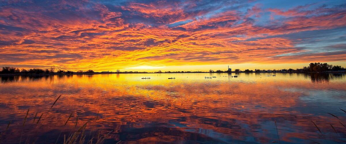 A sunset over a calm lake with vibrant orange and blue skies.