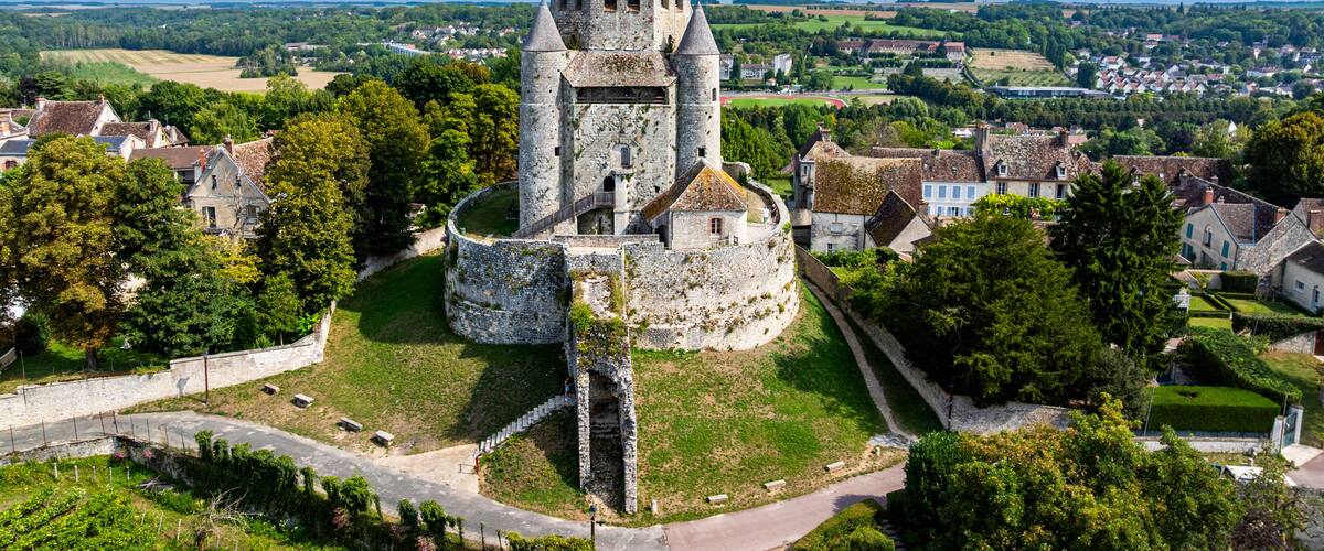 A historic stone tower surrounded by a fortified wall, with a village in the background.