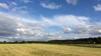 A wide-open field with a clear sky and scattered clouds.