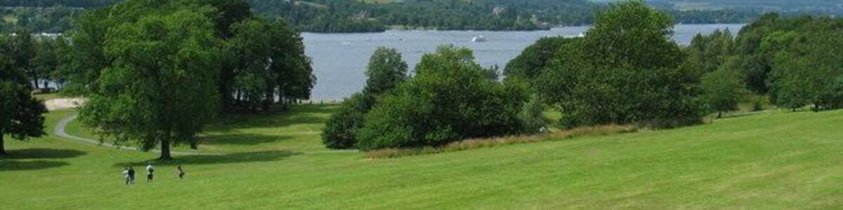 Ein grünes Feld mit einem See und Hügeln im Hintergrund.