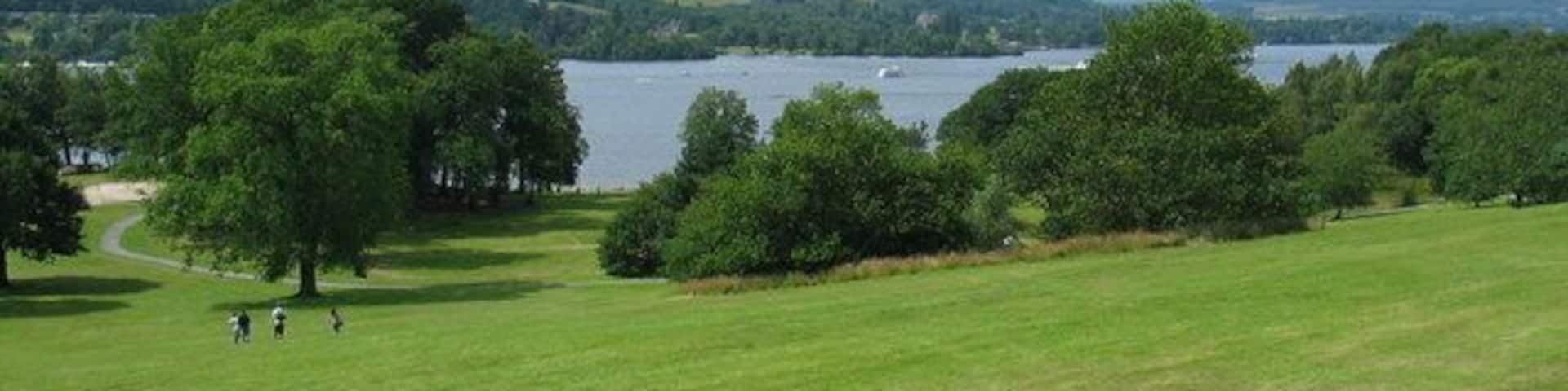 A grassy field with a lake and hills in the background.