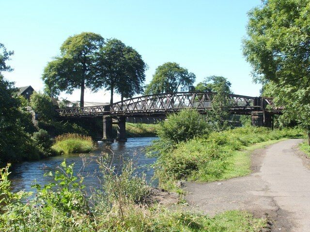 The Black Bridge. This bridge used to carry a railway line over the river (see 1131986), towards Dillichip Works (compare 1092625), but the line fell into disuse long ago. The bridge was subsequently used by pedestrians, but, at the time of writing, it has been closed to the public for several year. On this side of the river, the cycle path (NCN Route 7) passes under the bridge. The buildings on the other side of the river are bonded warehouses, a fact that probably accounts for the blackness of the trees here, if not that of the bridge itself (see 971102).