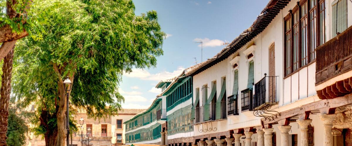 A tree-lined street with outdoor seating and historic buildings.