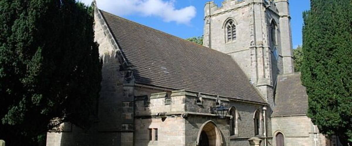 A stone church with a tall bell tower and arched entrance.