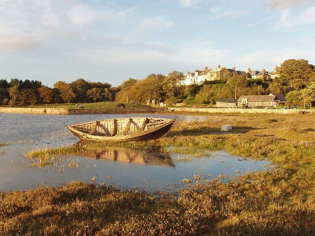 A boat stranded in a shallow water body with a village in the background.