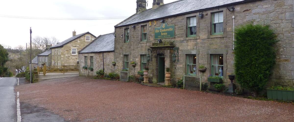 A stone building with a sign reading "The Tankerville Arms Free House."