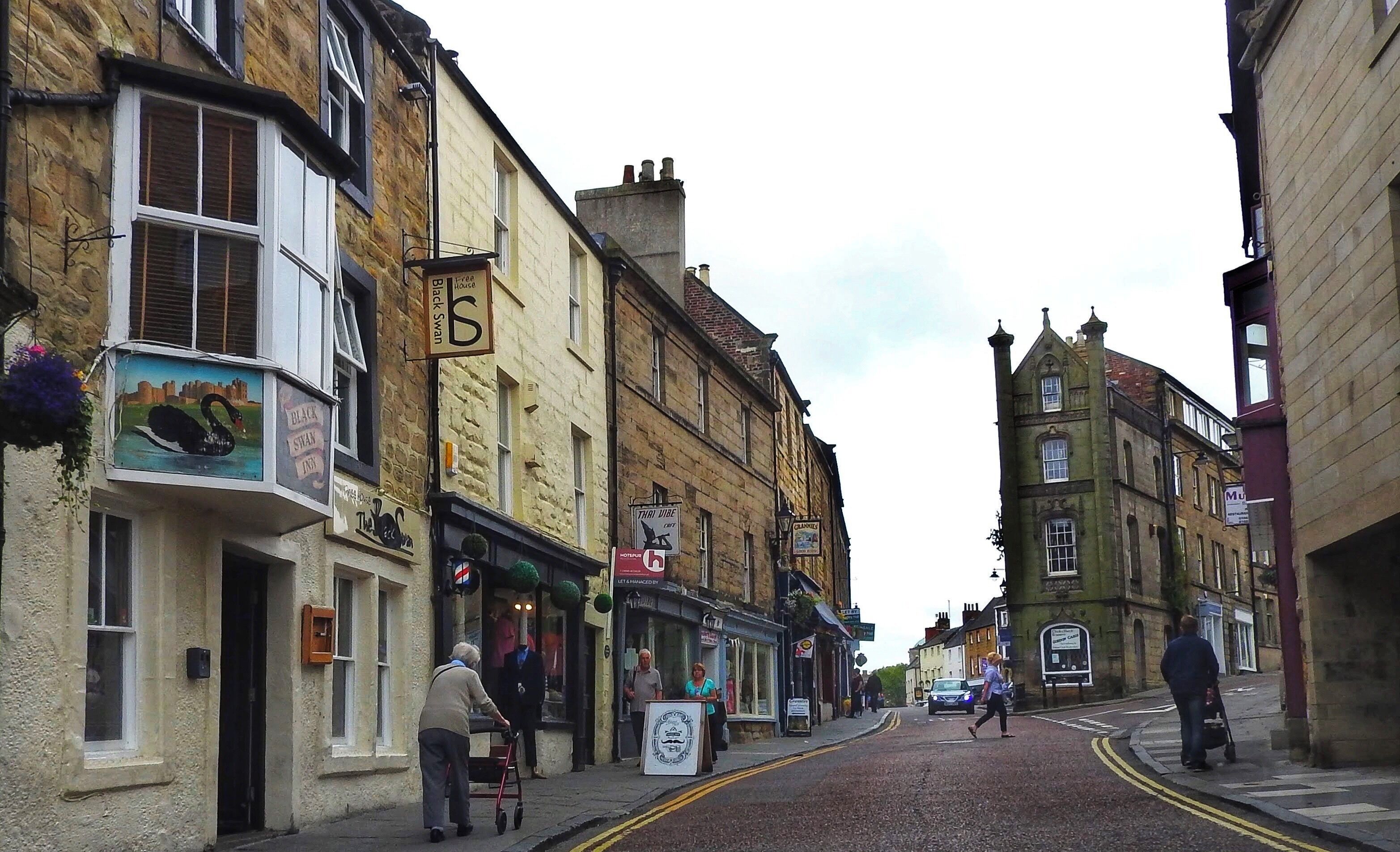 A street scene in Alnwick, England, near the Alnwick Castle. Shot taken along Narrowgate with Fenkle Street forking off to the right. (June 2017)