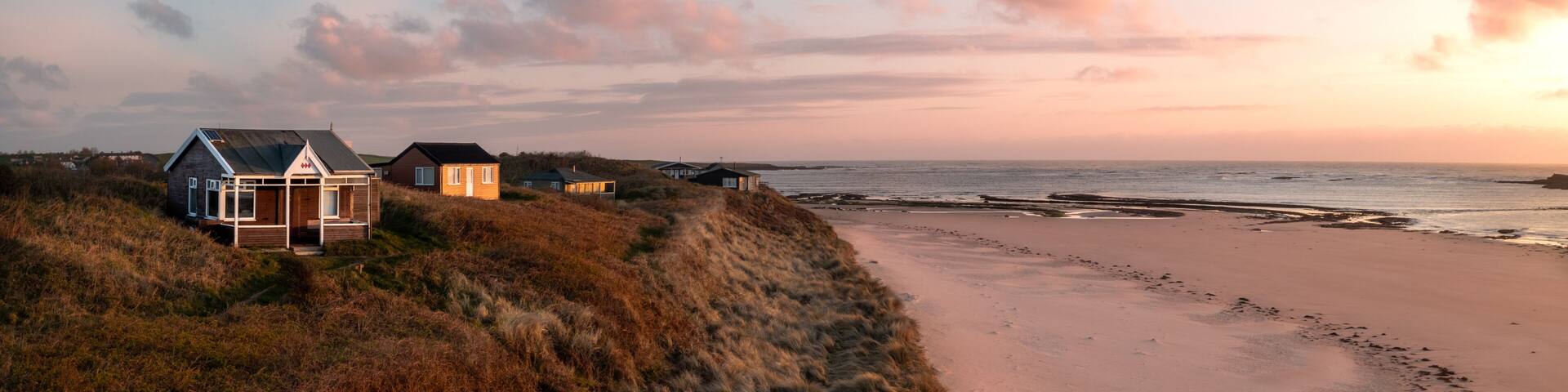 Aerial view of remote beach huts on the Northumberland coast at Embleton Bay beach at sunrise