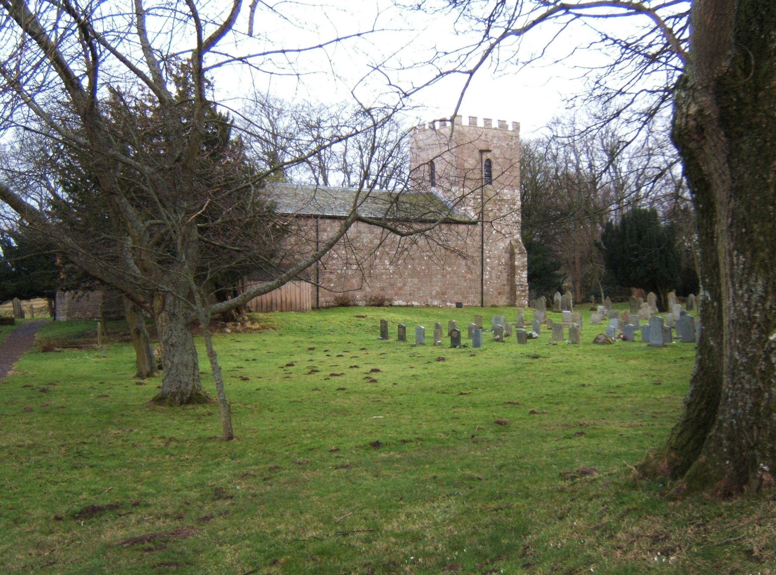 A church with a tower and a cemetery with headstones.