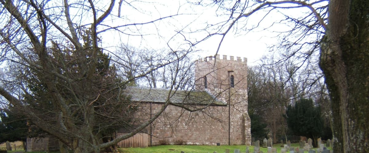 A church with a tower and a cemetery with headstones.