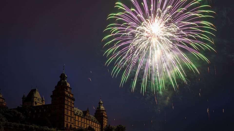 Un castillo con múltiples torres y un espectáculo de fuegos artificiales en el cielo.