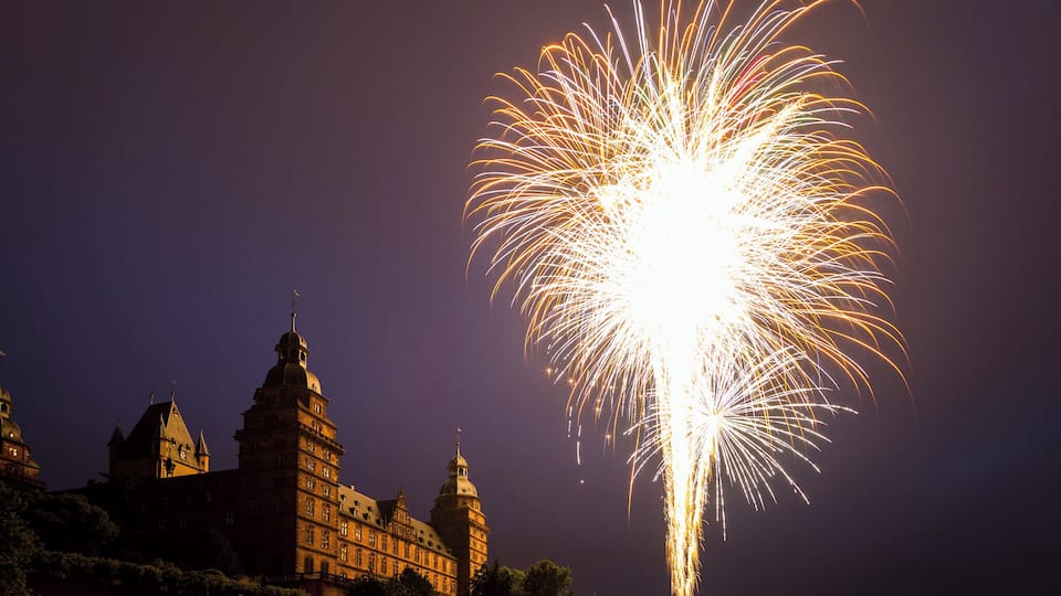 Un edificio histórico con múltiples torres y un gran espectáculo de fuegos artificiales en el cielo.