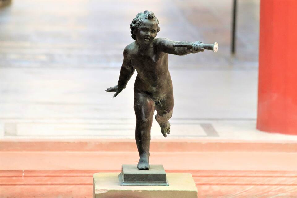 A bronze statue of a child on a pedestal.