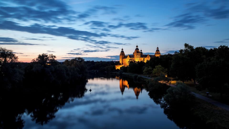 Un complejo de templos al anochecer, con reflejos en un río tranquilo.