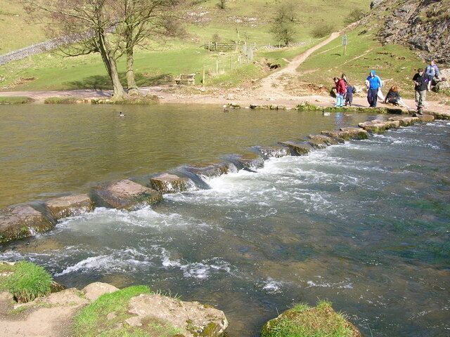 A river flowing over rocks with people walking nearby.