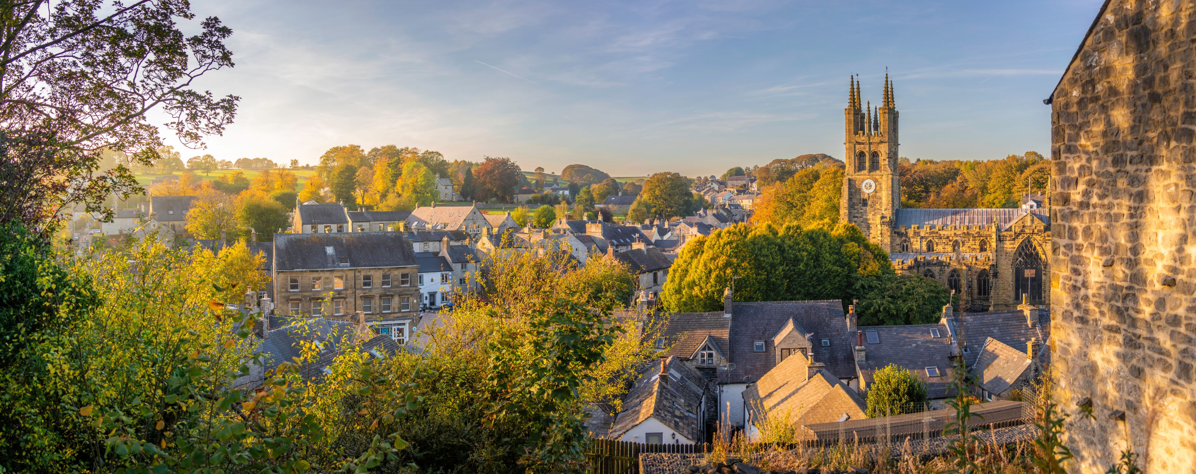 A historic town with a prominent church tower, dense foliage, and traditional architecture.
