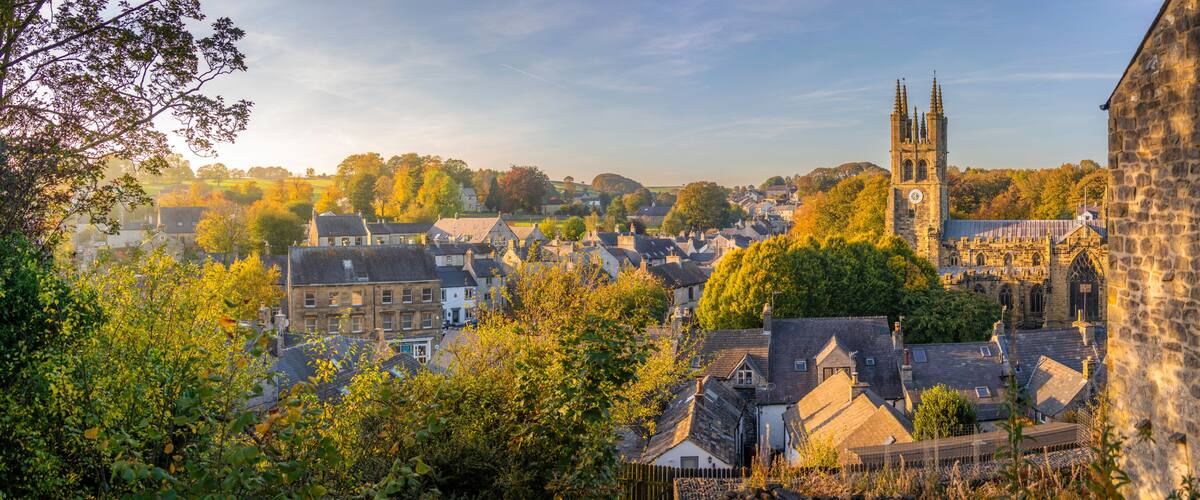 A historic town with a prominent church tower, dense foliage, and traditional architecture.