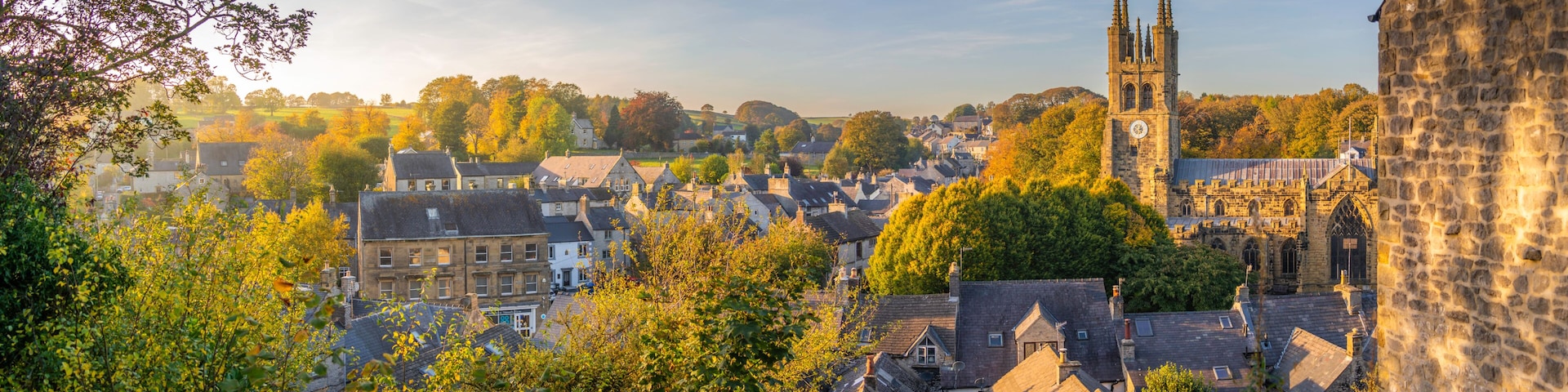 A historic town with a prominent church tower, dense foliage, and traditional architecture.
