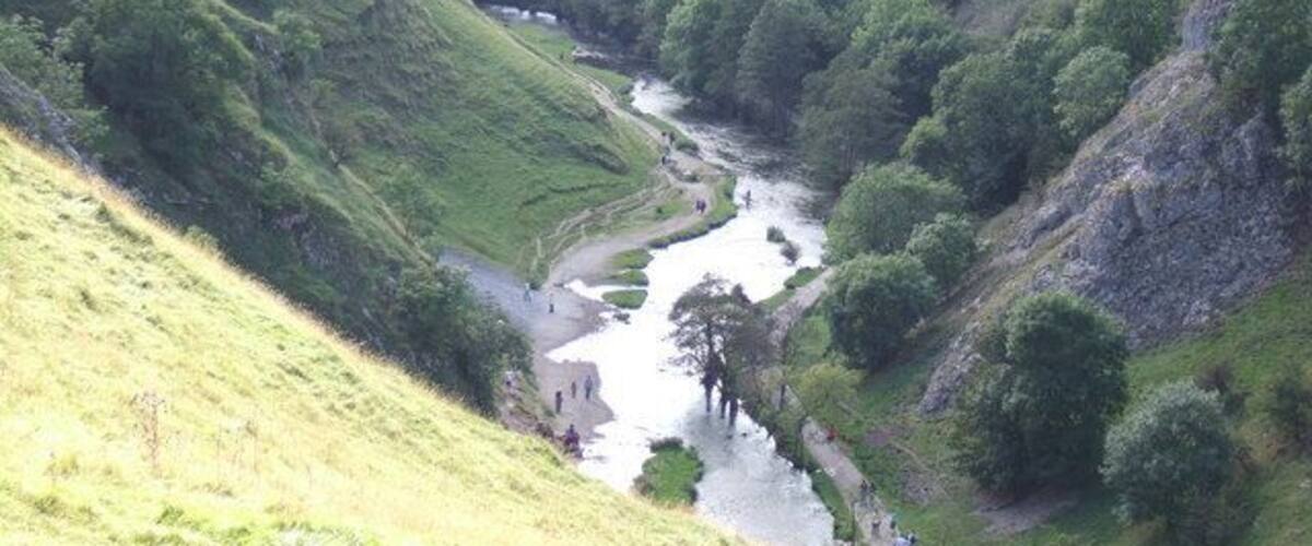 A river winding through a valley with steep hills and dense greenery.
