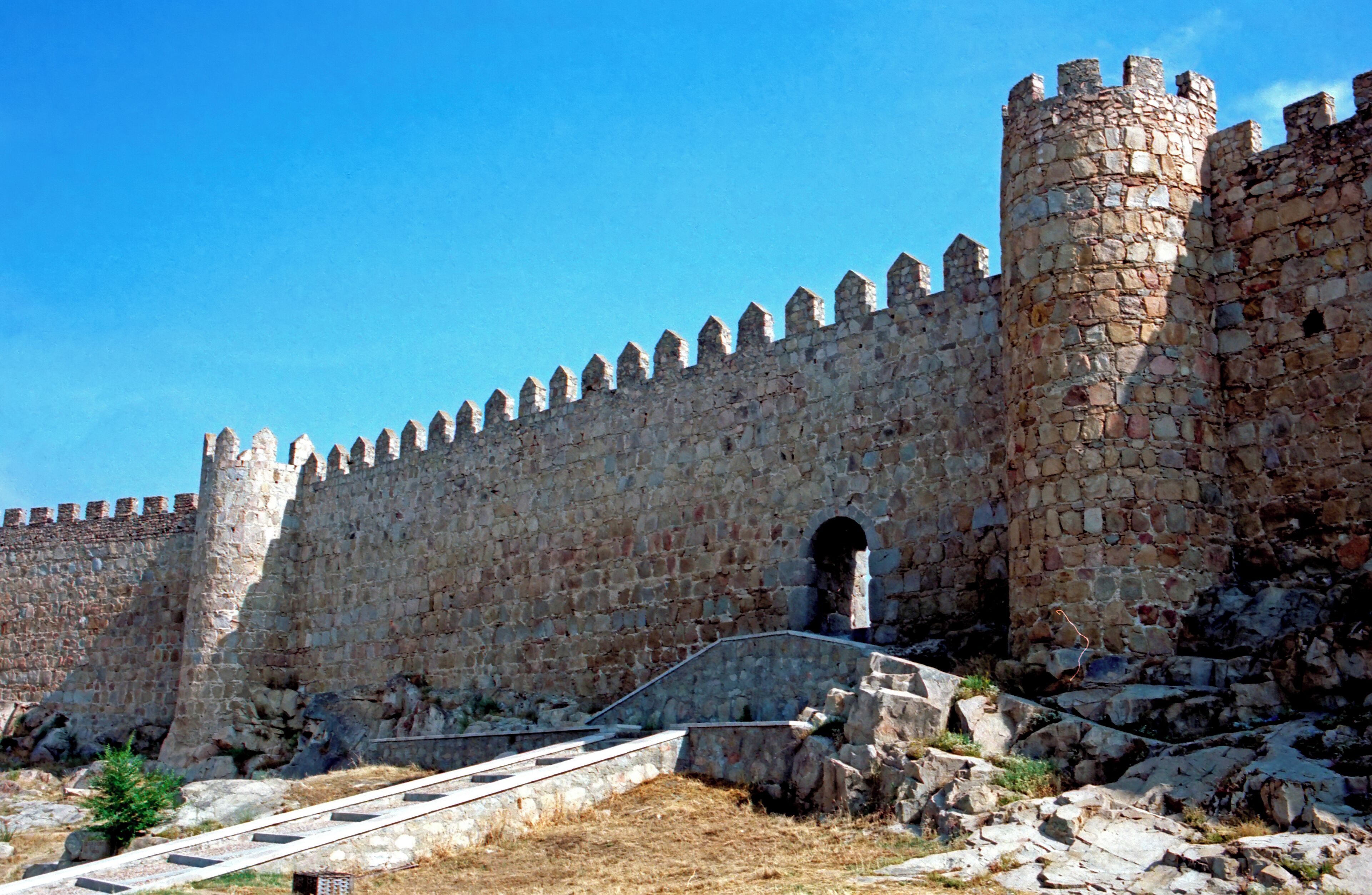 A stone castle with a high wall and a large tower.