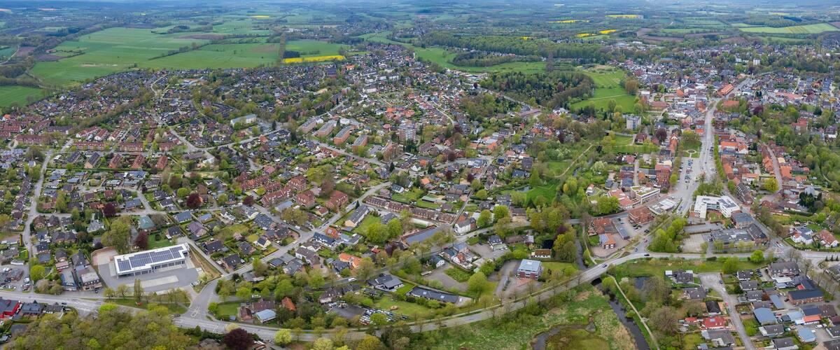An aerial view of a densely populated town with residential houses, roads, and green fields.