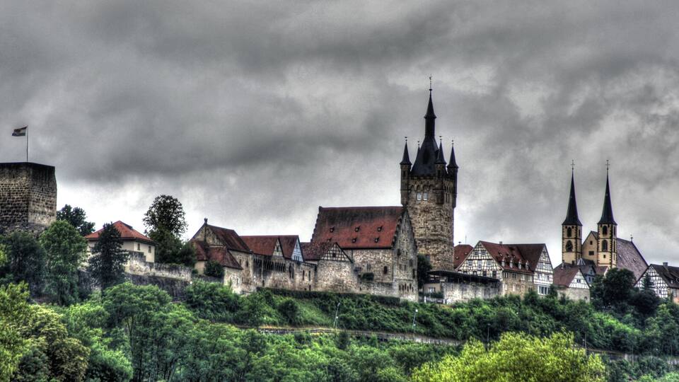 A historic town with medieval architecture, including a prominent tower and church spires.