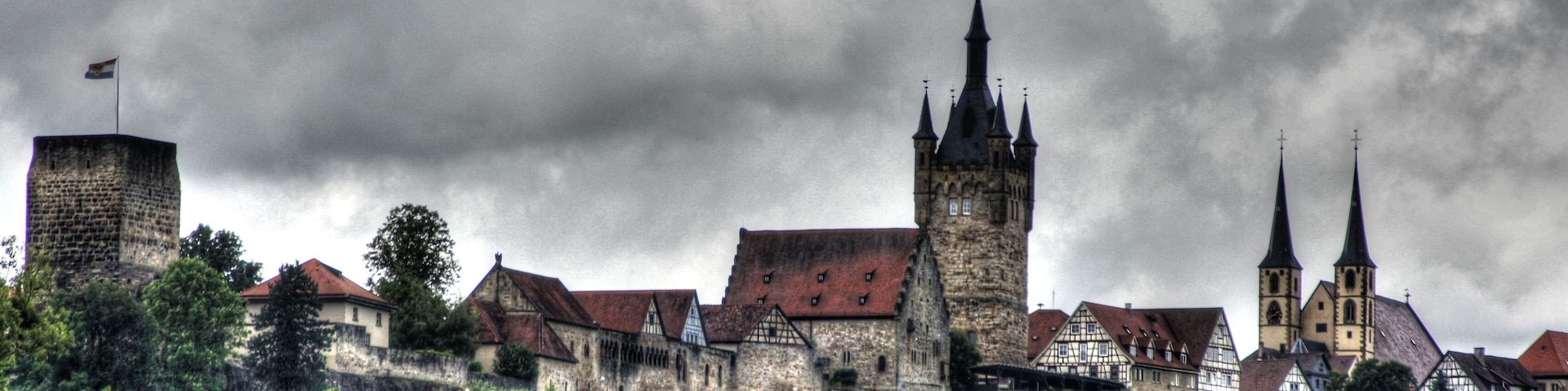 Uma cidade histórica com arquitetura medieval, incluindo uma torre imponente e torres de igreja.