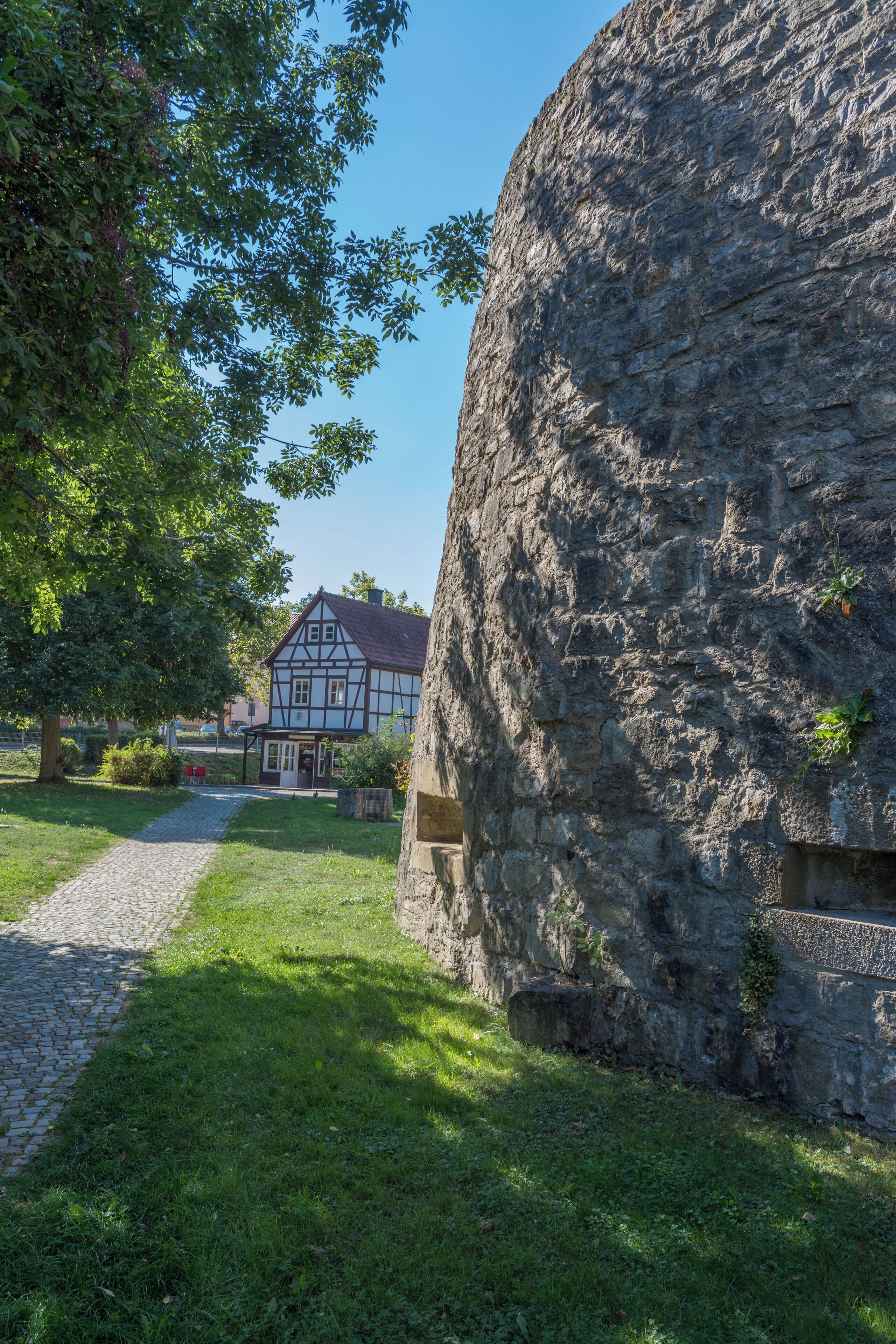 A stone wall, a house, and a tree.