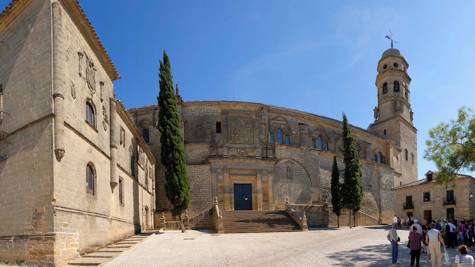 Un bâtiment historique doté d’une cour intérieure, de grands cyprès et d’un clocher.