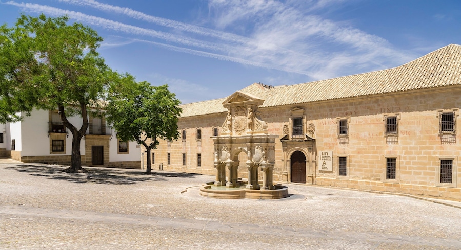A historic building with a courtyard, a fountain, and a tree.