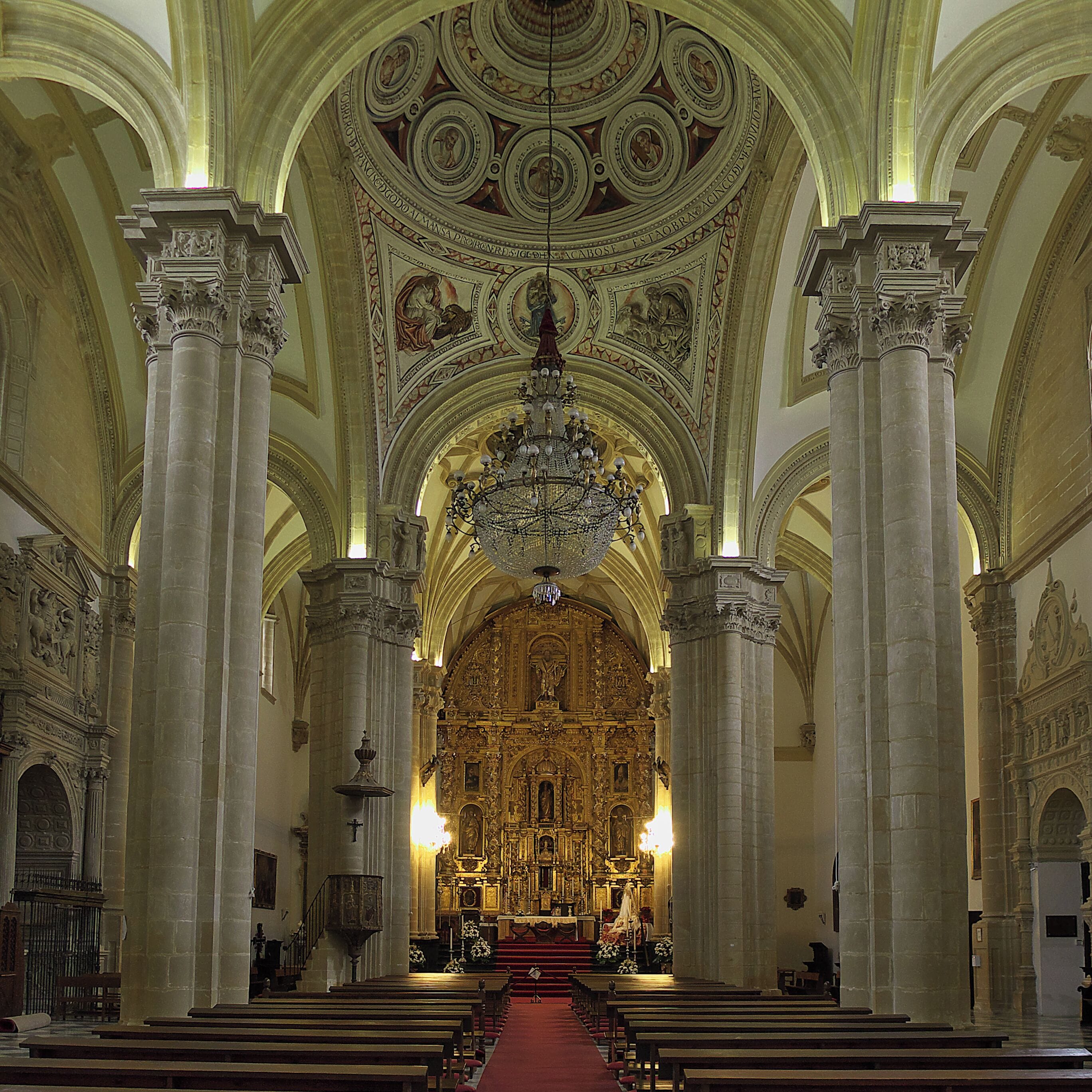L’intérieur d’une église richement décorée, avec de hauts plafonds, des fresques détaillées et un autel central.