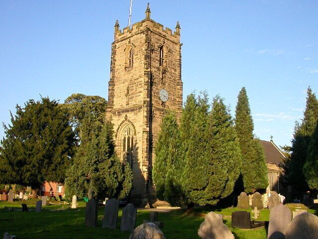A historic church tower surrounded by a cemetery with gravestones.