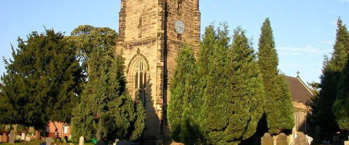 A historic church tower surrounded by a cemetery with gravestones.