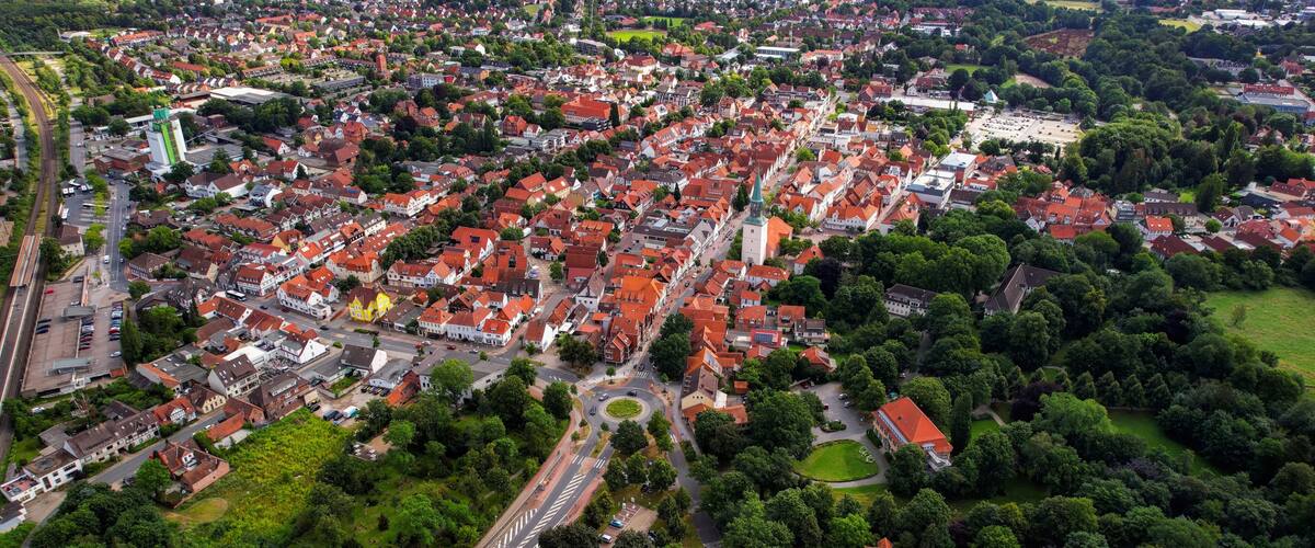 An aerial view of a densely populated town with red-roofed houses, a prominent church, and a railway line.